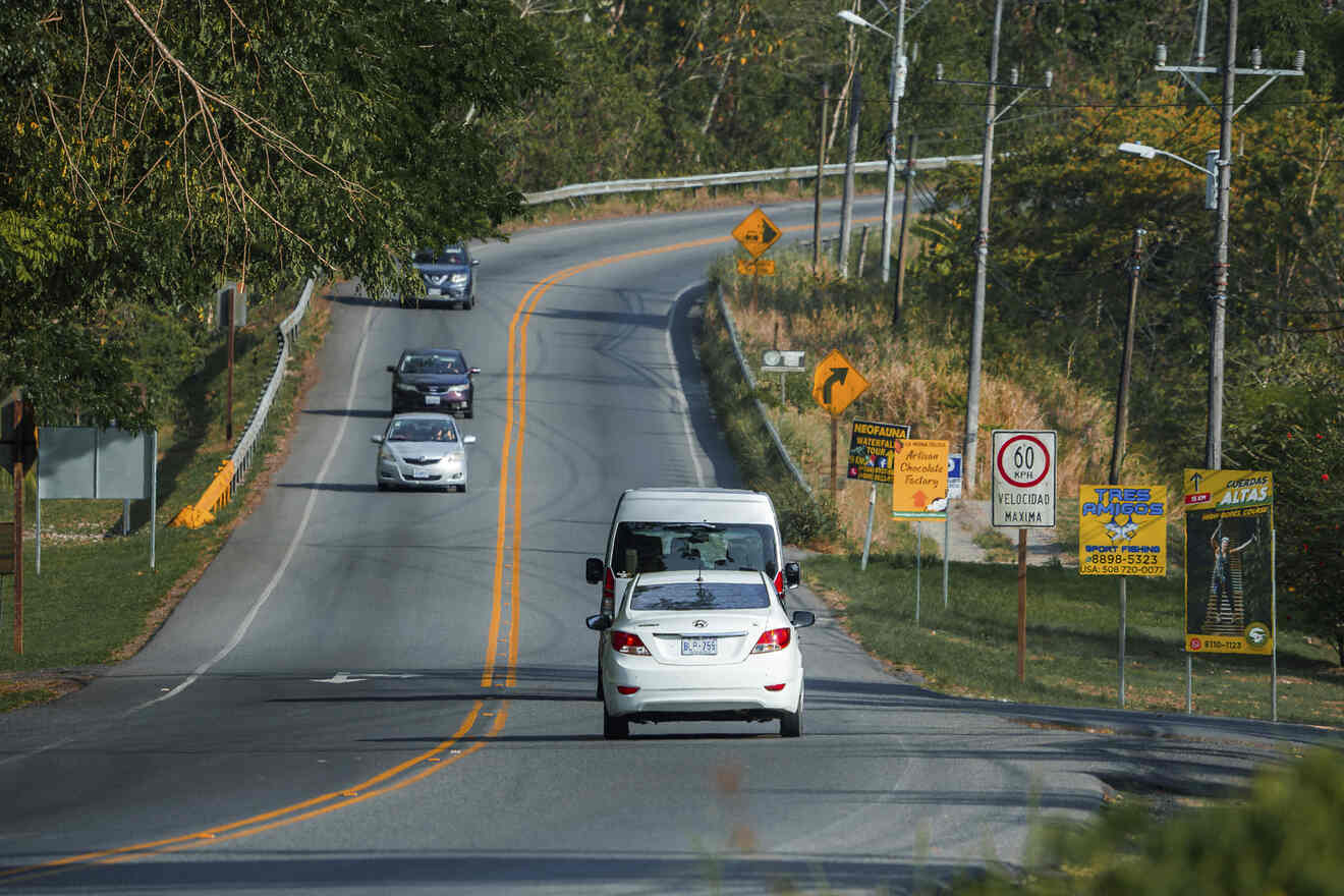 Cars are driving down a road with a sign on it.