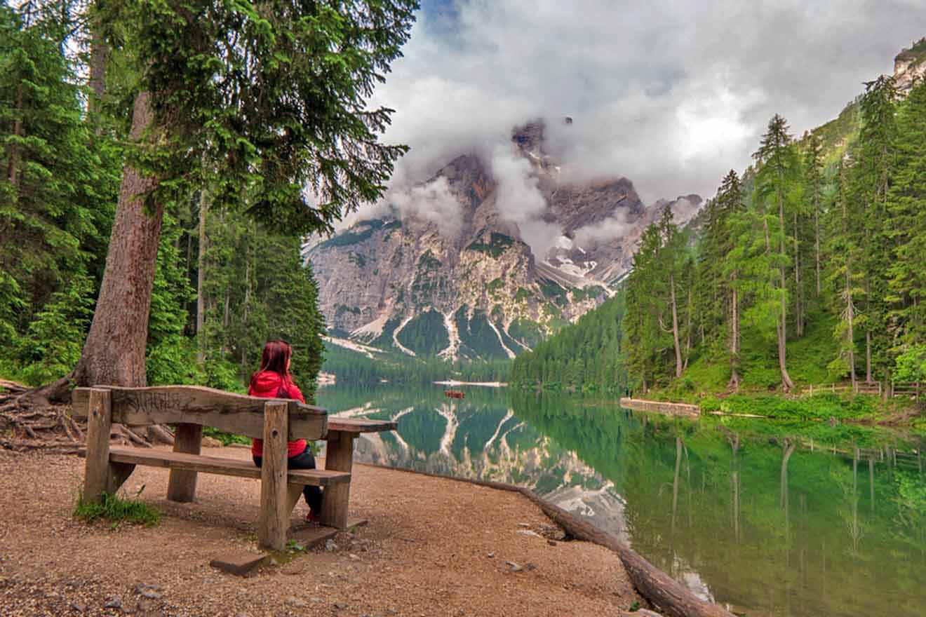 A woman sits on a bench overlooking a lake.