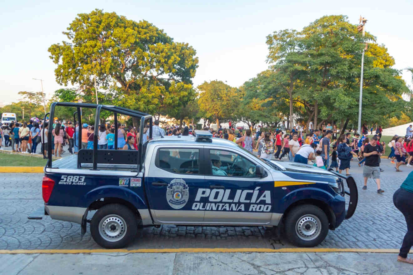 A police car is parked in front of a crowd of people.