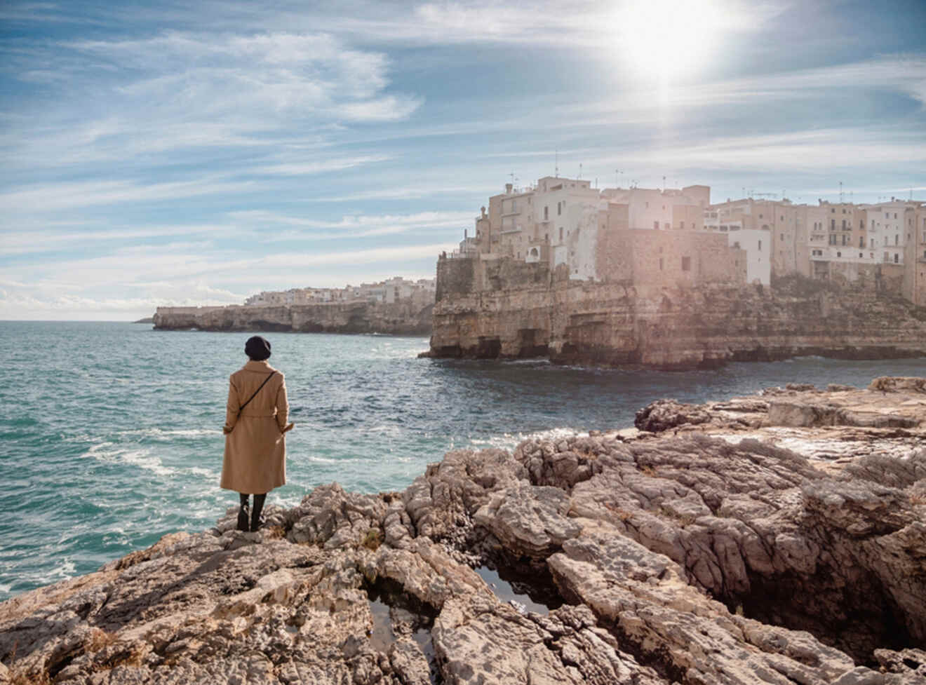 a person standing on the edge of rocks looking at a city