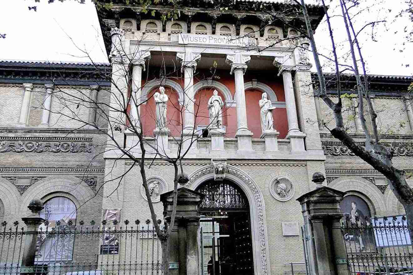 a building with statues on it with trees in front of it