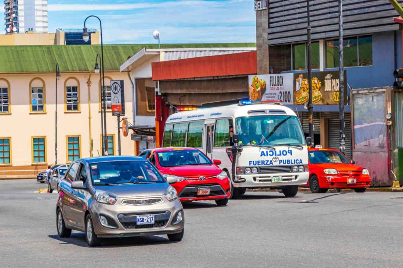 A police bus and cars driving down a street.