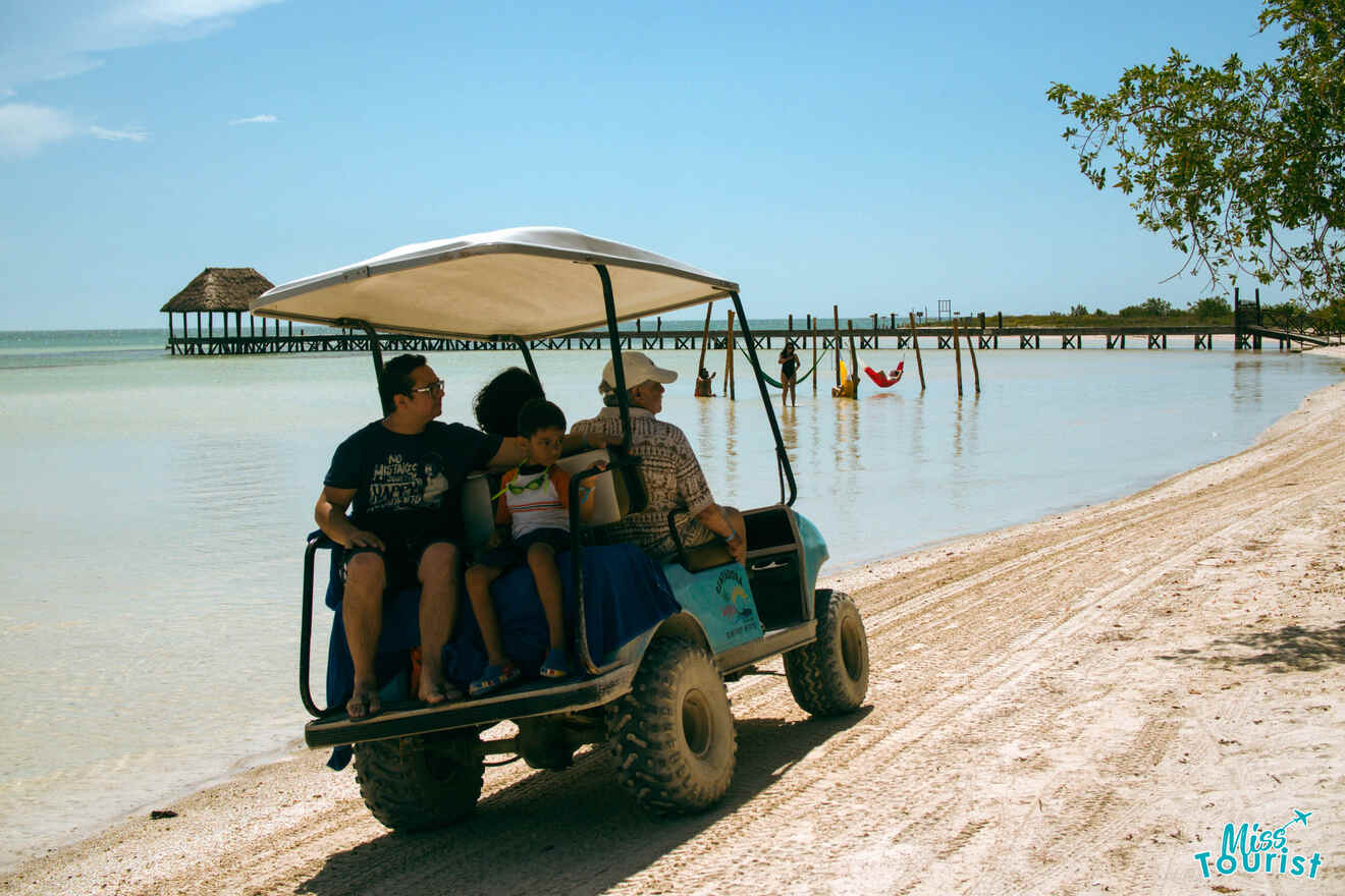 A group of people riding in a golf cart on a beach.