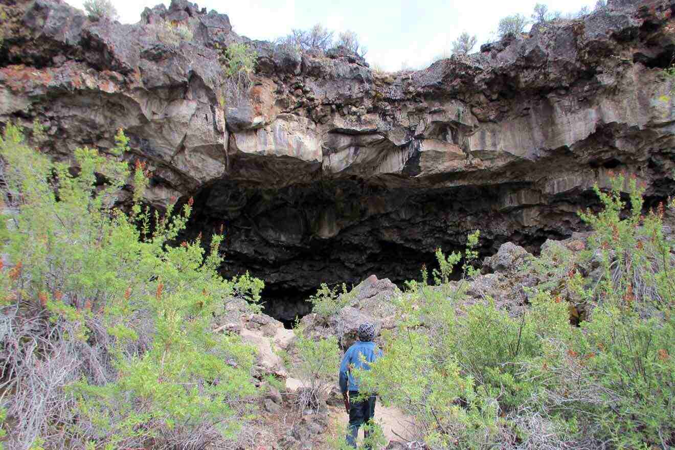 A person standing in front of a cave.