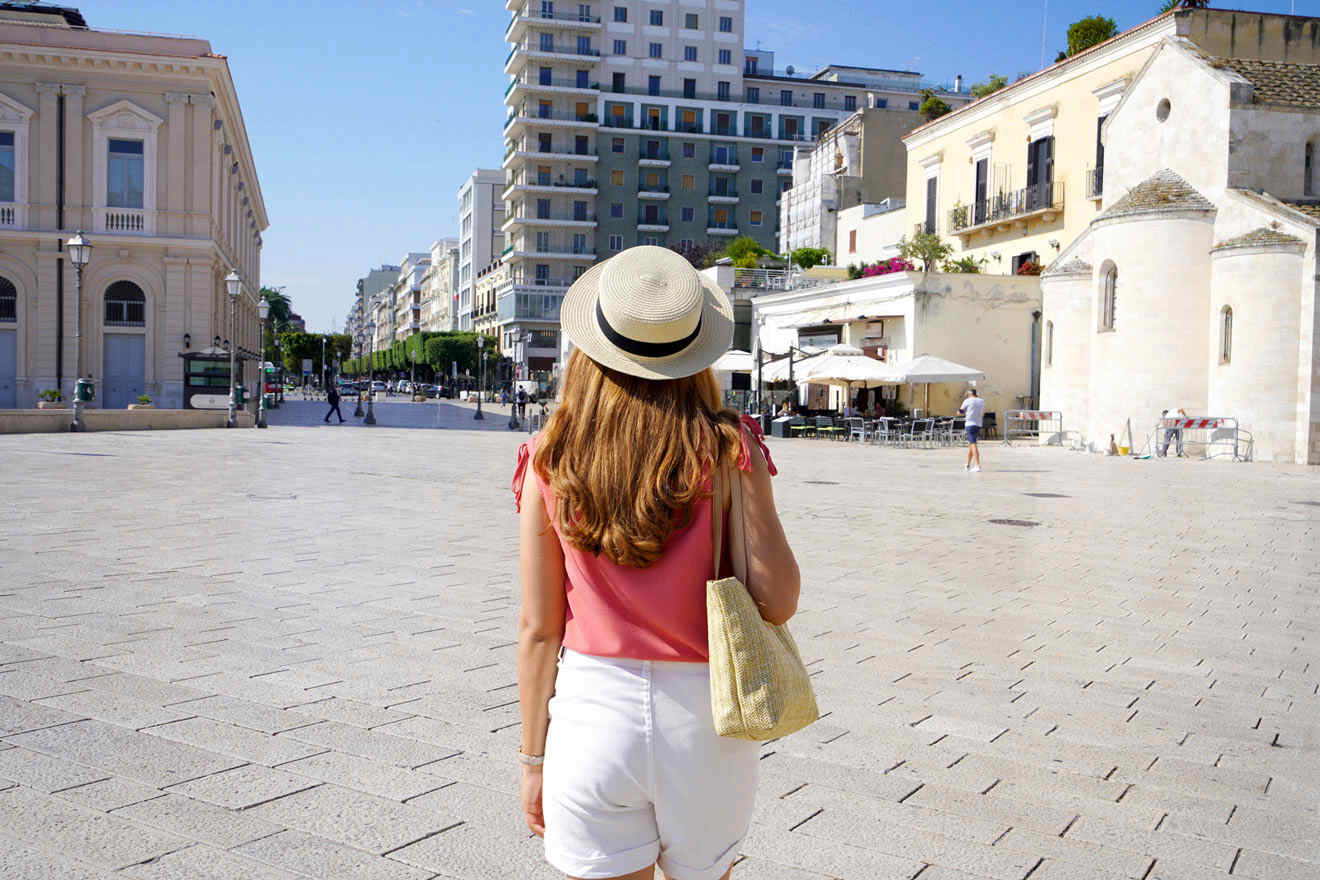 A woman wearing a hat and shorts walking down a city street.