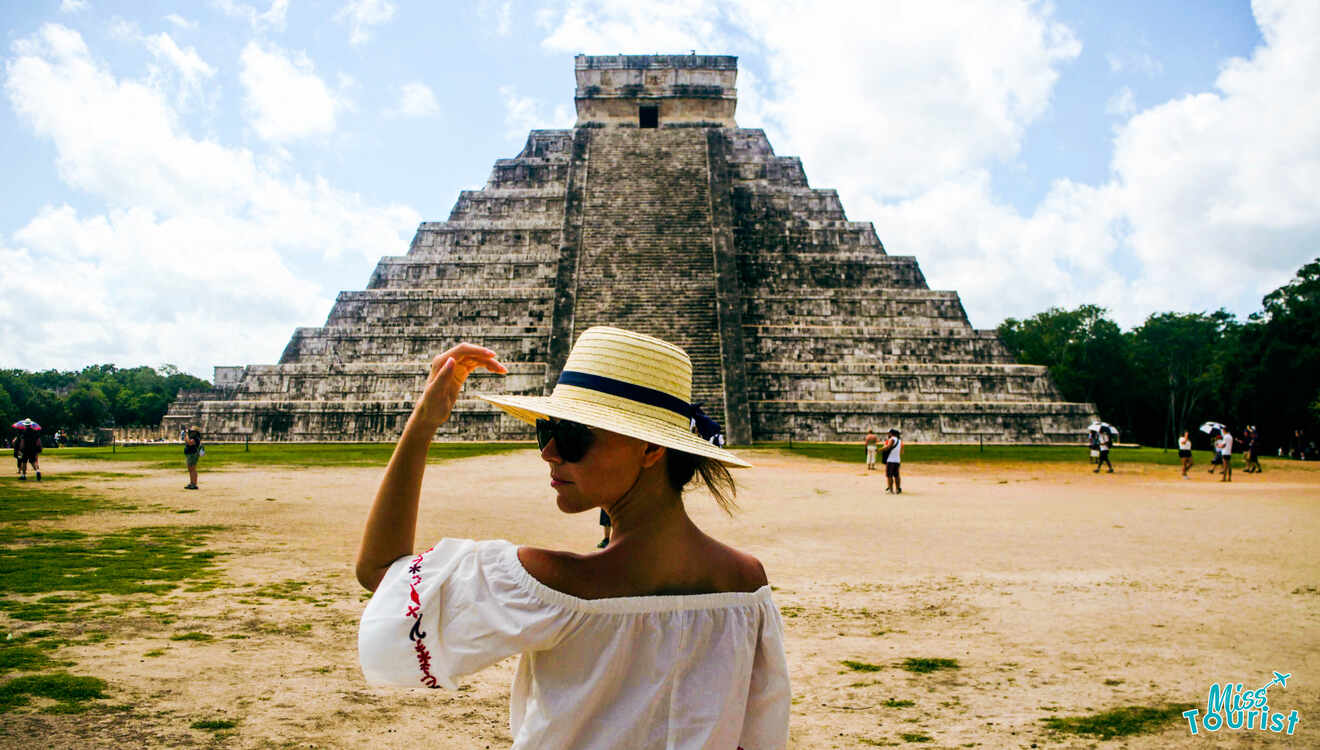 A woman in a hat in front of a pyramid in chichen itza.