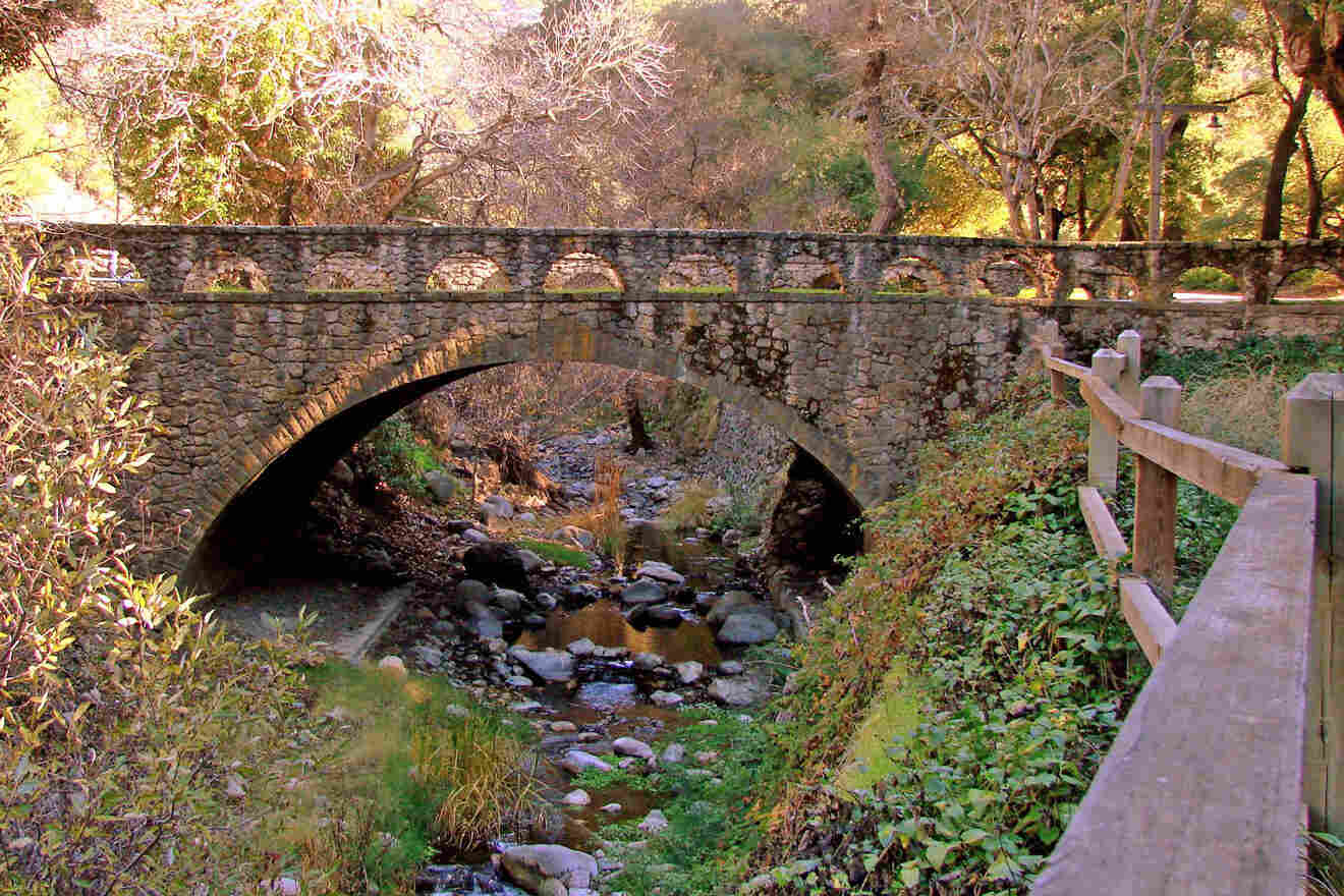 A stone bridge over a stream in a wooded area.