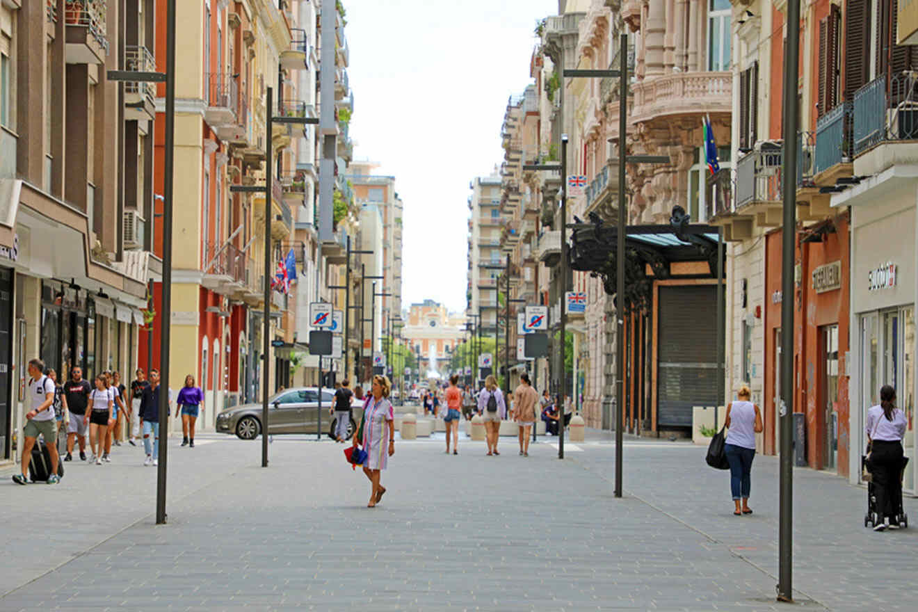 People walking down a street in a city with various shops