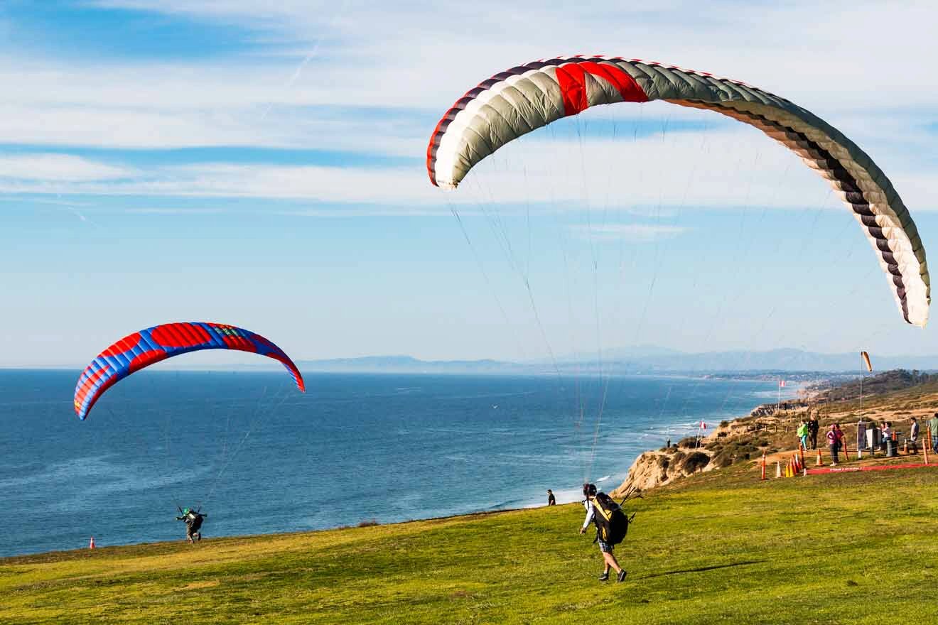 people paragliding from a hill overlooking the ocean