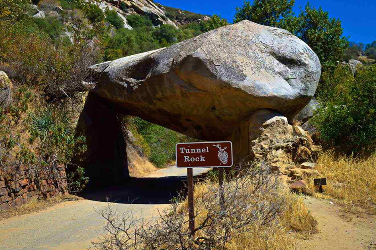 A large rock over the road with a sign next to it