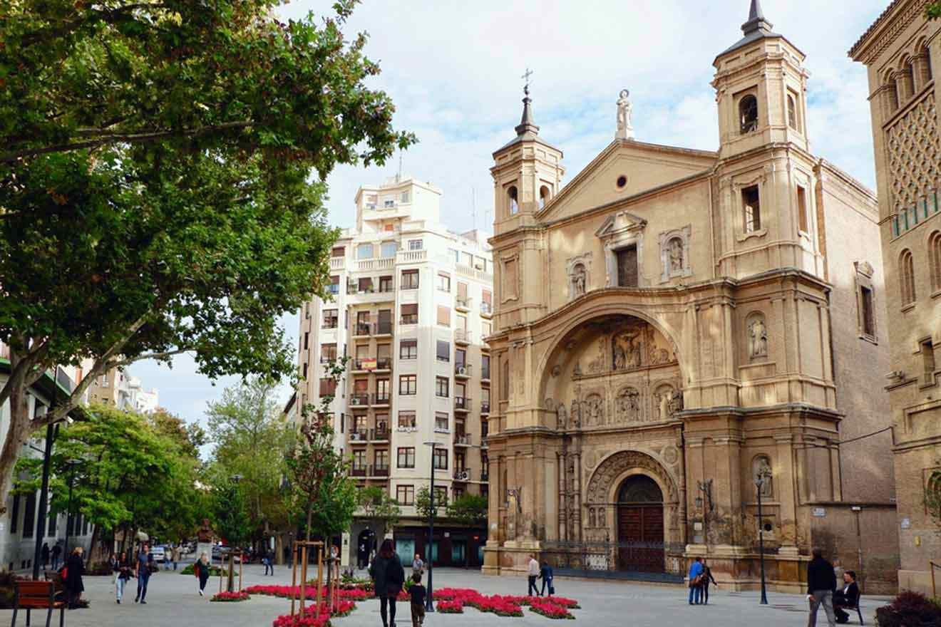 a group of people walking down a street next to a church and other tall buildings