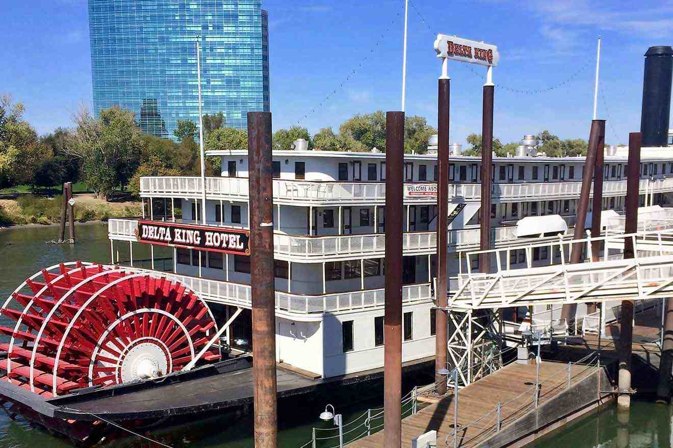A river boat housing a hotel docked in front of a building.
