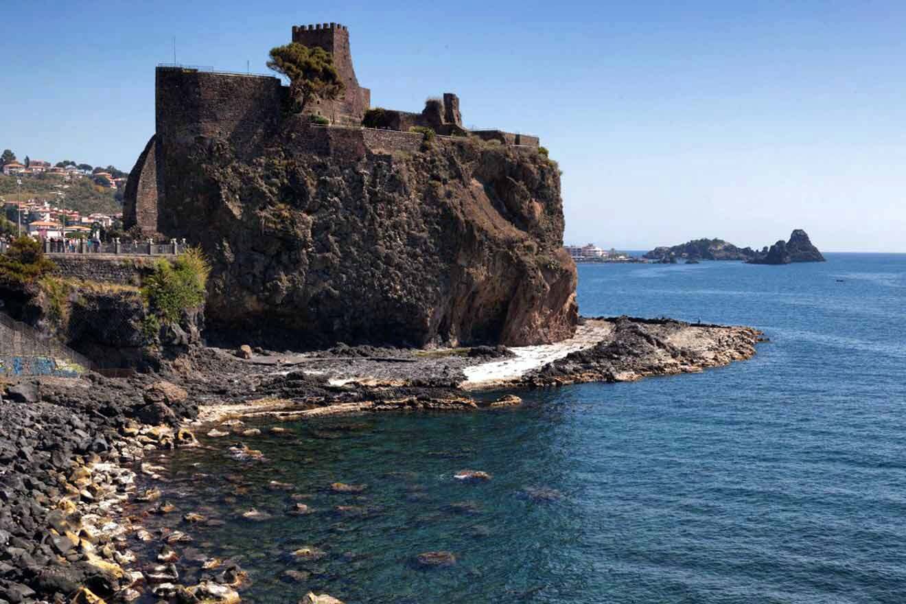 A castle sits on top of a cliff overlooking the ocean.