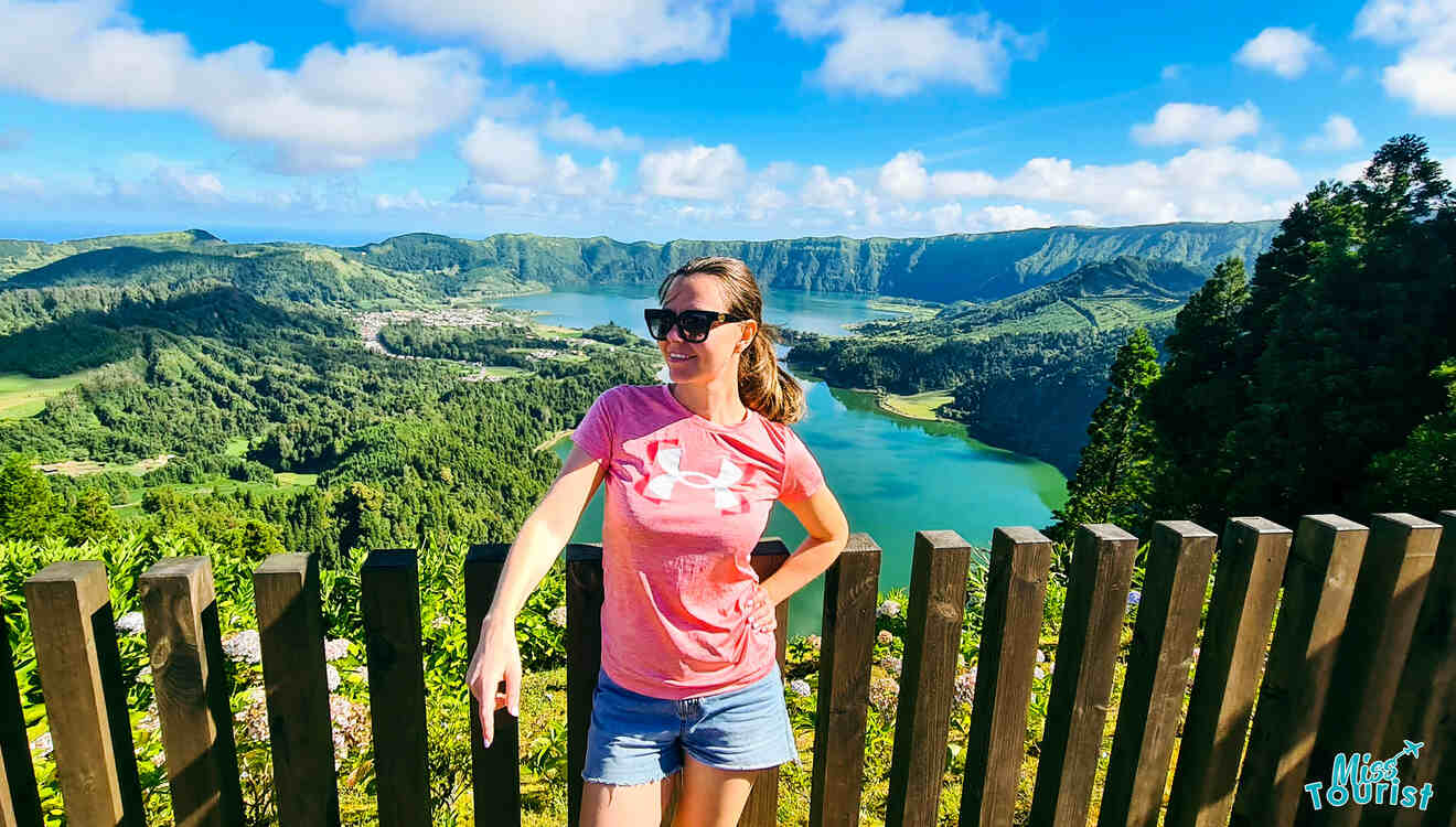 A woman standing in front of a fence in front of a lake.