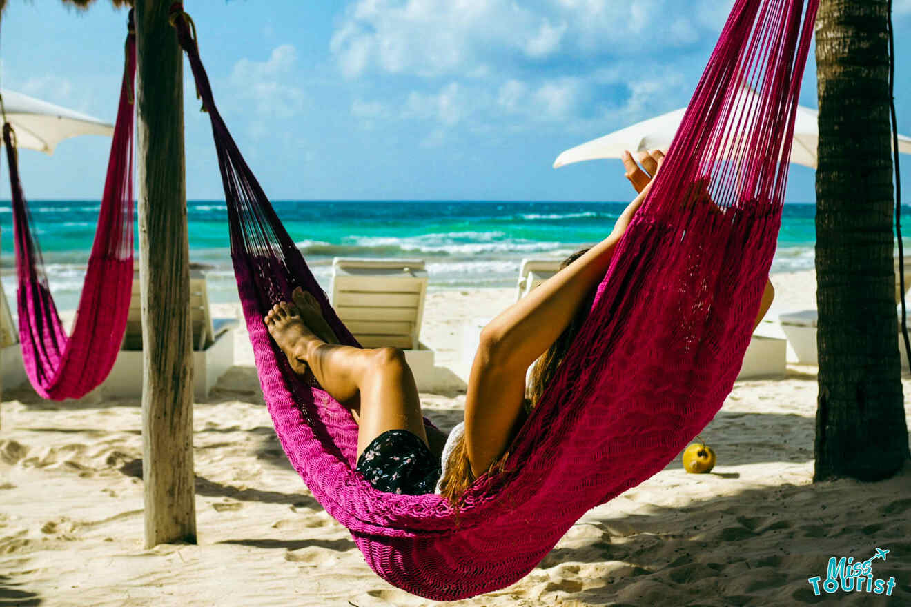A woman is relaxing in a pink hammock on the beach.