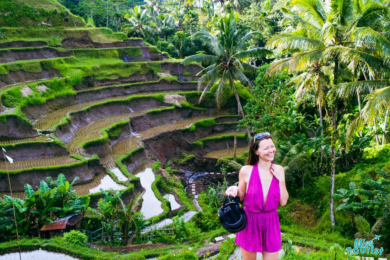 A woman in a purple dress standing in front of rice terraces.