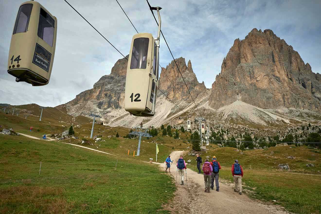 A group of people walking down a trail with a cable car in the background.
