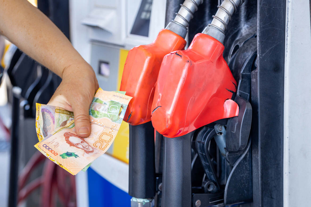 A person is putting money into a gas pump.