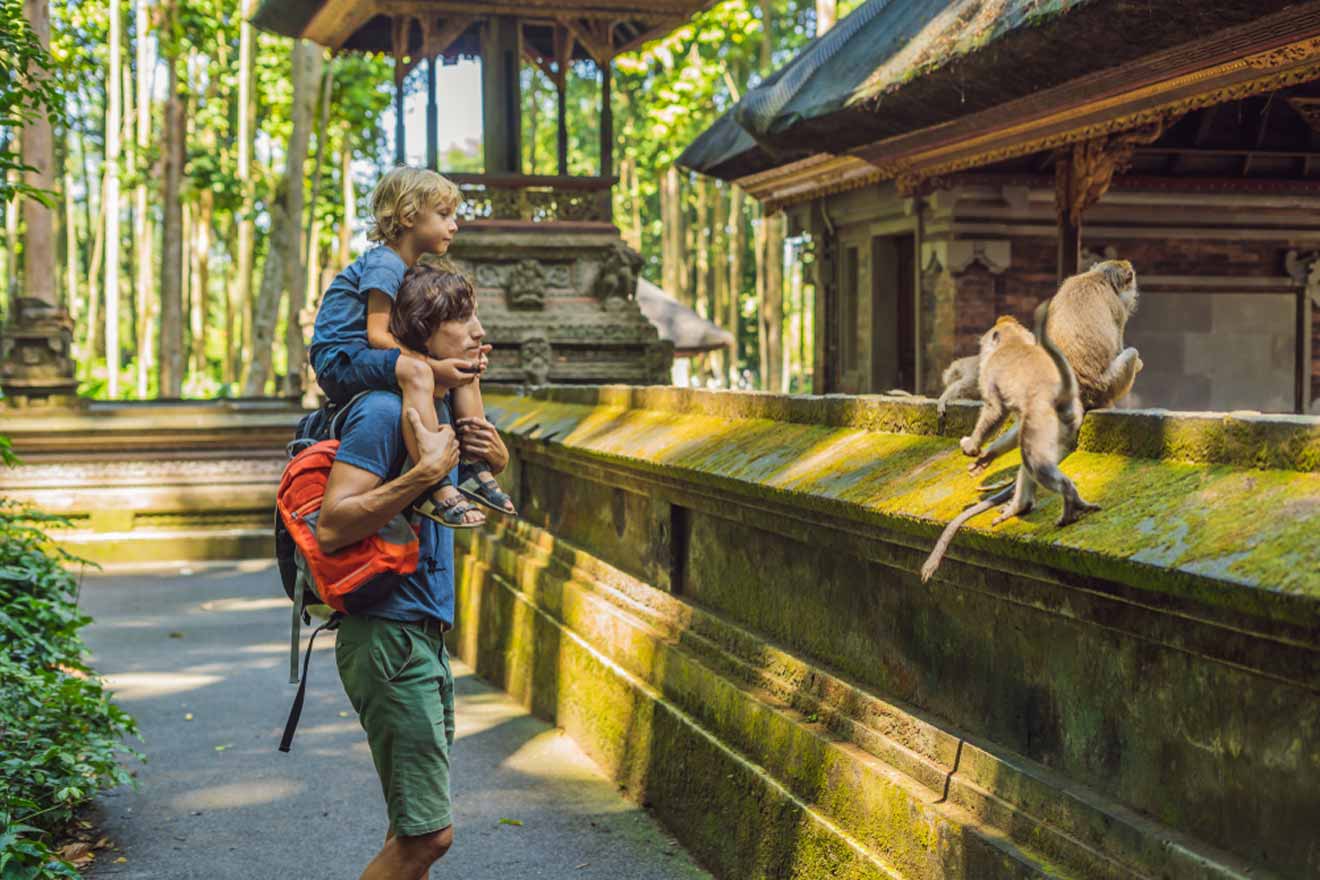 A man and a child are holding a backpack looking at monkeys