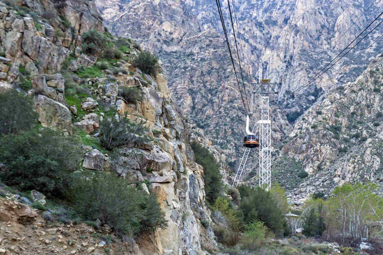 A cable car is going up a mountain in a canyon.