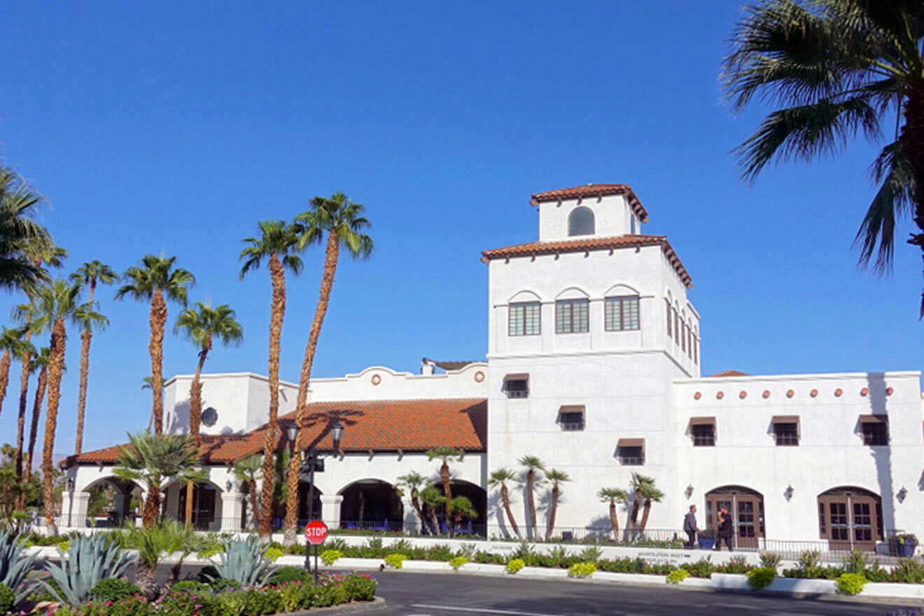 A white building with palm trees in front of it.