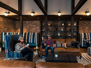 Two men sitting in a room with couches and a fireplace.