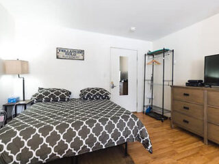 A bedroom with a bed, dresser and tv.