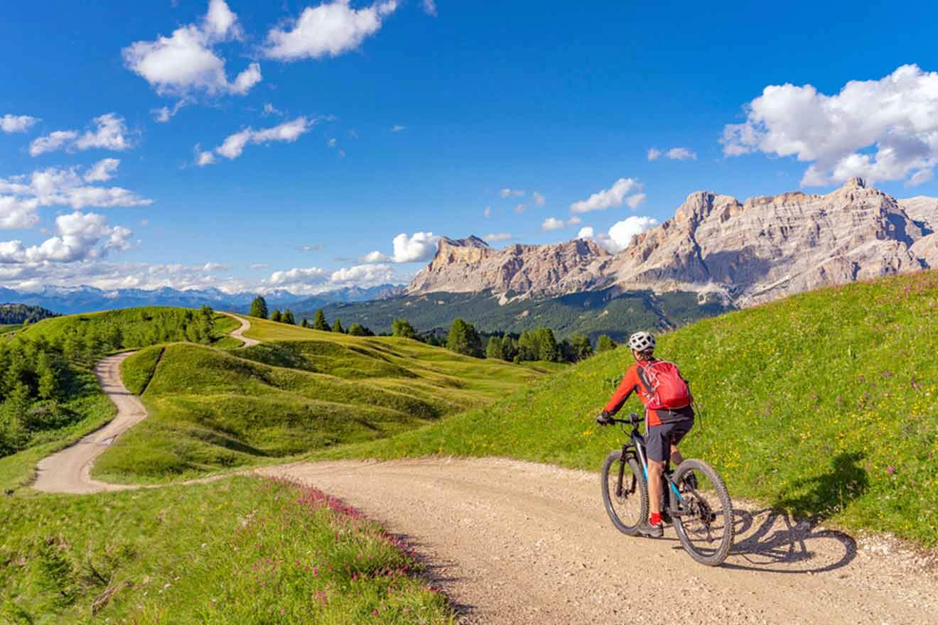 A person riding a mountain bike on a dirt road in the dolomites.