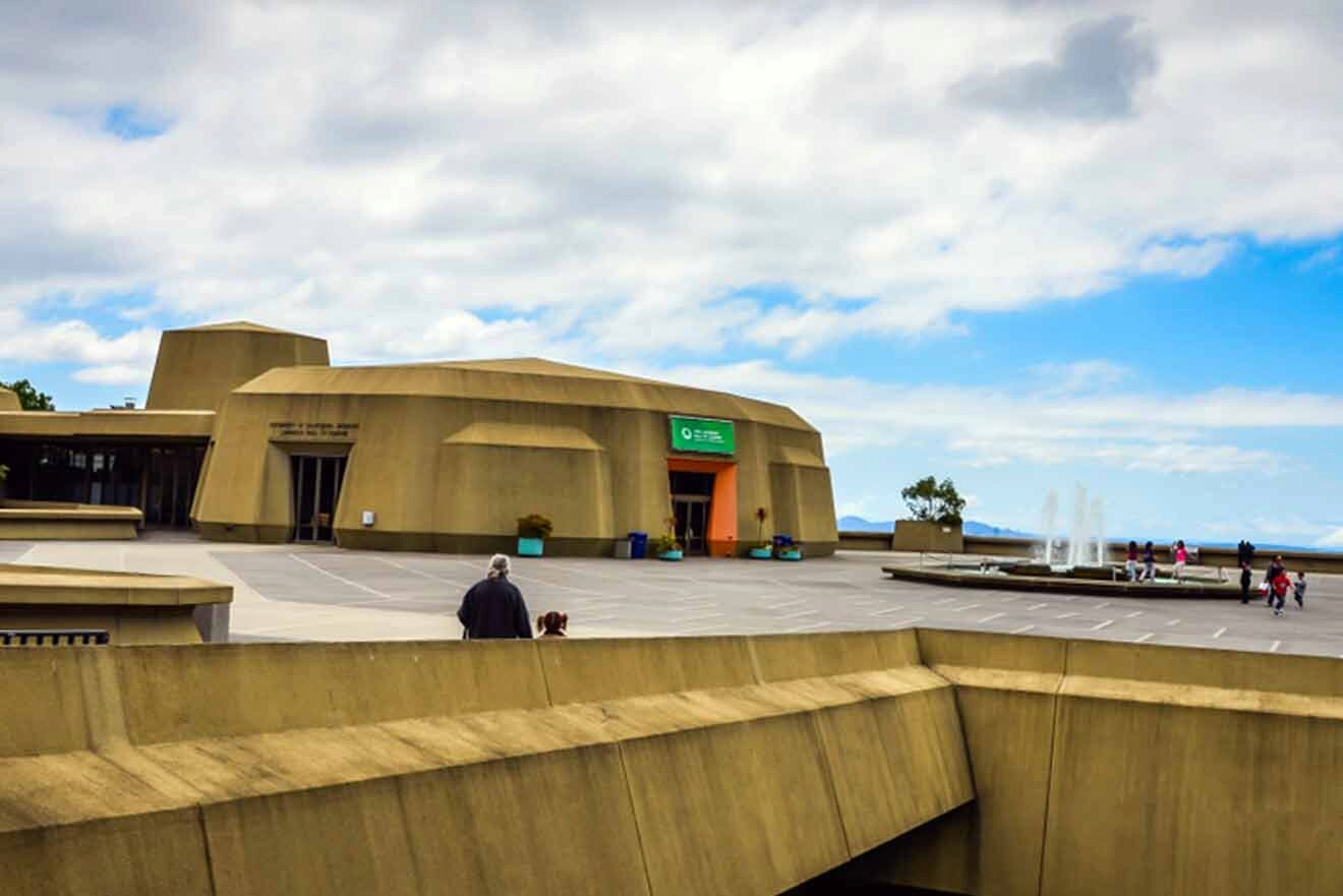 People walking around a building with fountain next to it