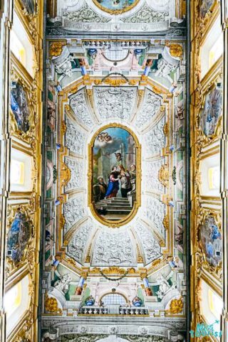 The ceiling of an ornate building with paintings on it.