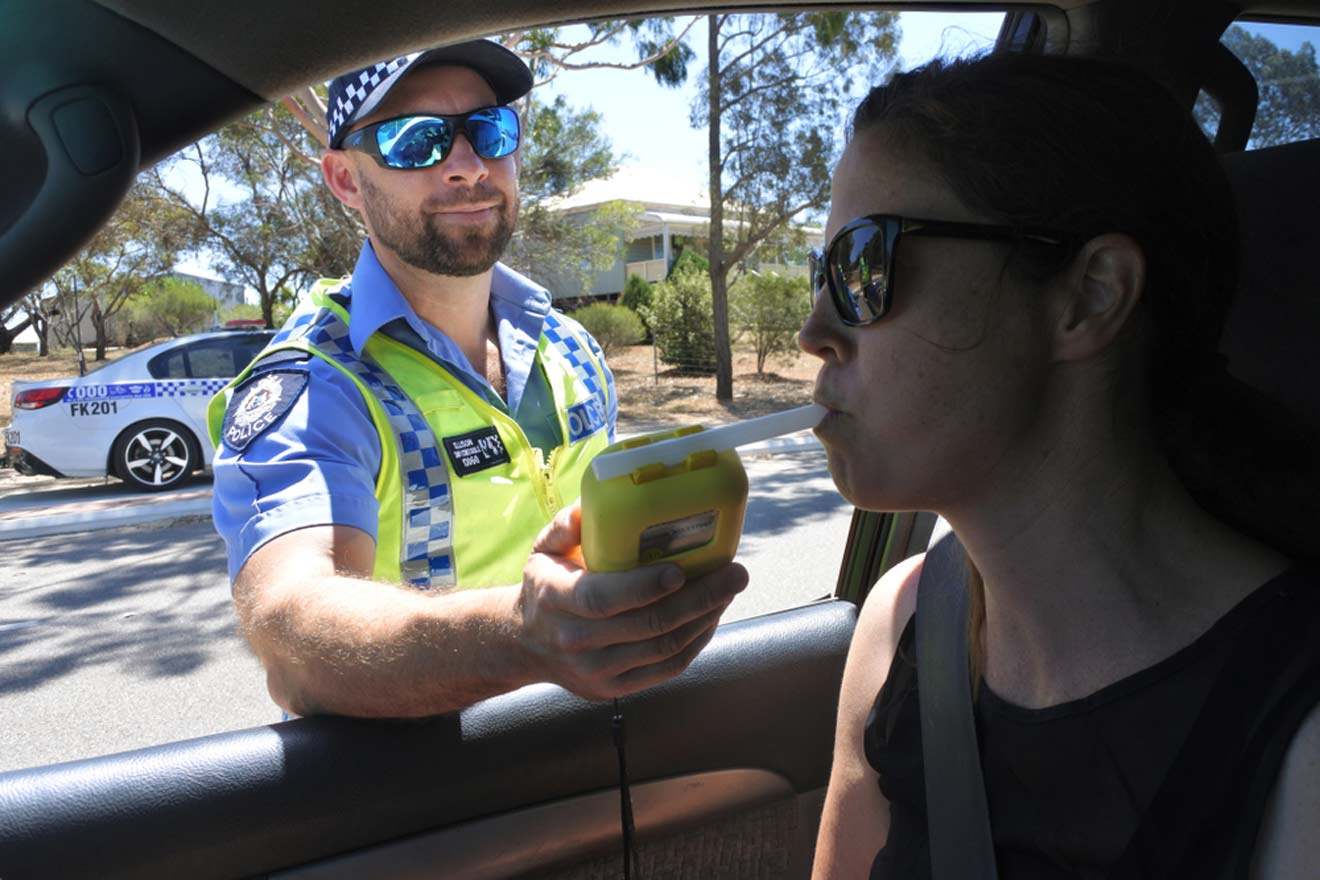 A police officer is giving breathalyzer for woman in a car