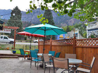 A patio with tables and chairs in front of a mountain.