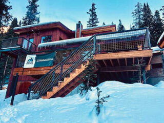 A house in the snow with stairs leading up to it.