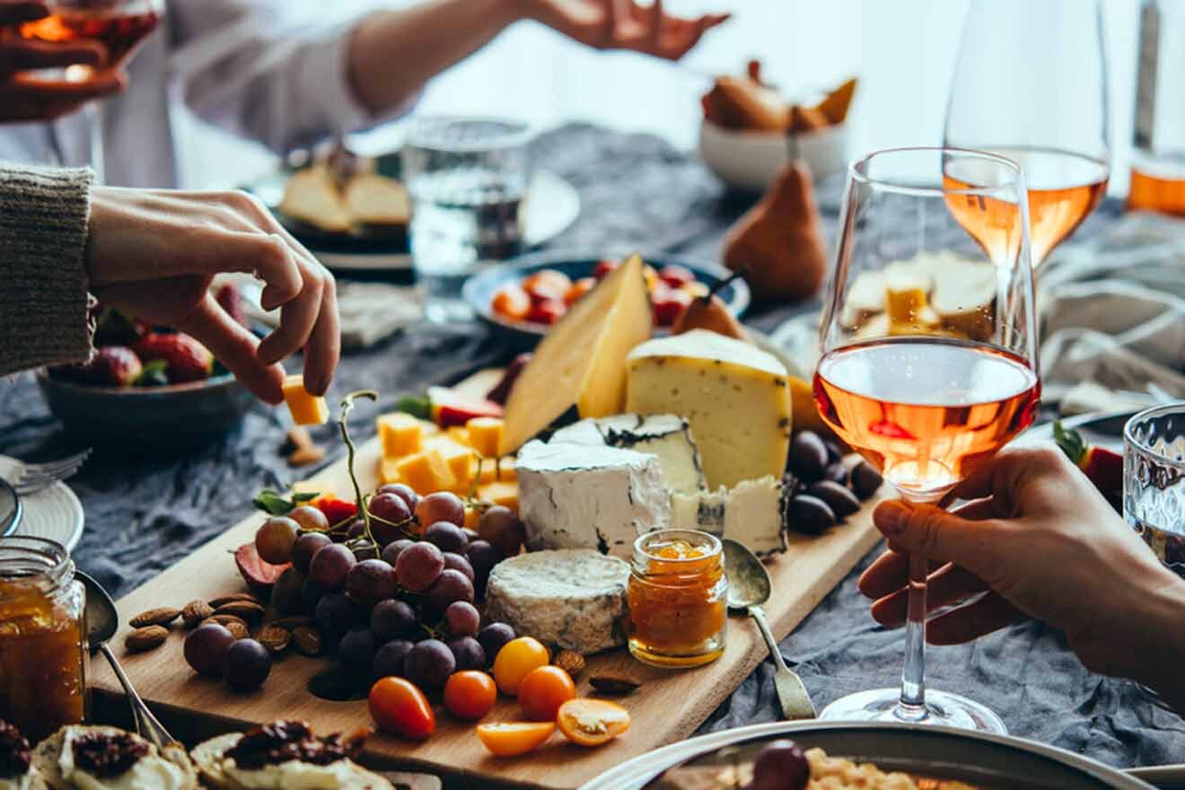 A group of people toasting wine and cheese at a table.