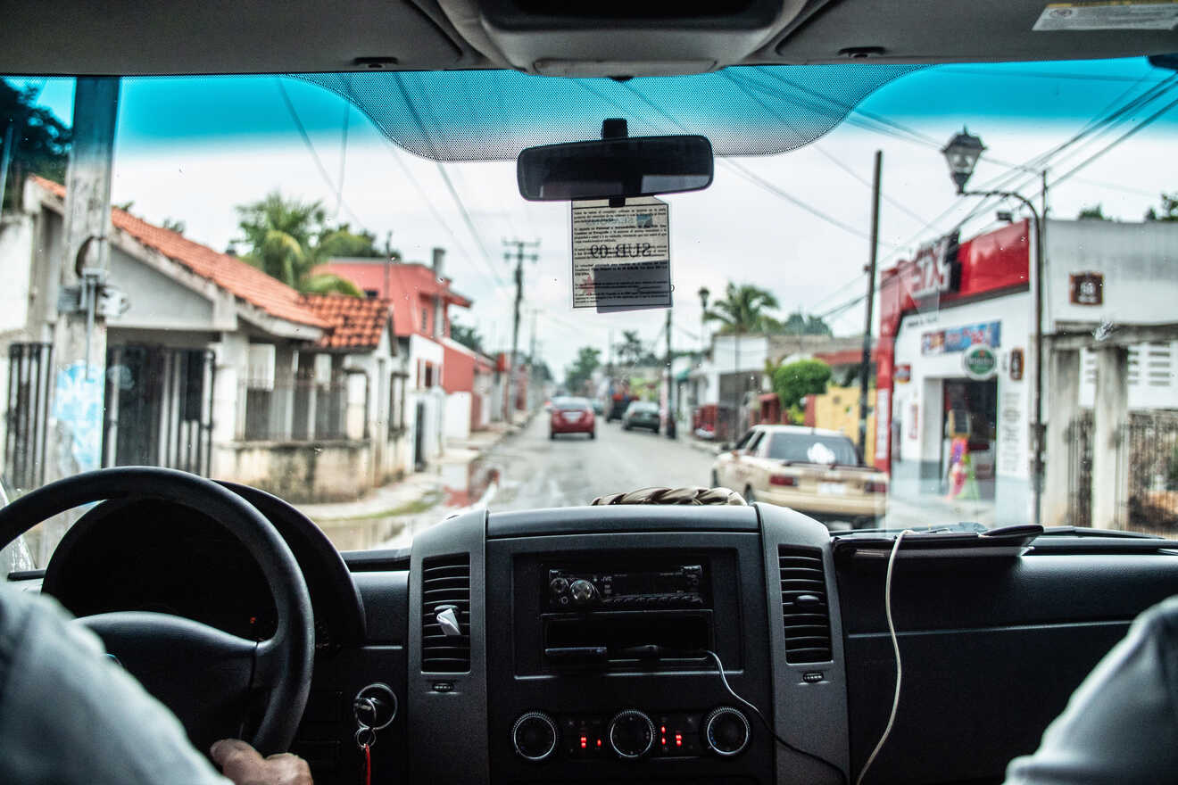 Two men in a car driving down a street.