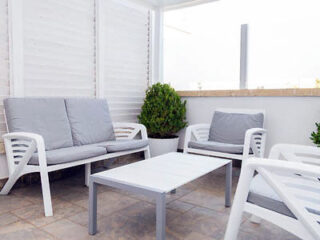 A white patio with white furniture and a table.