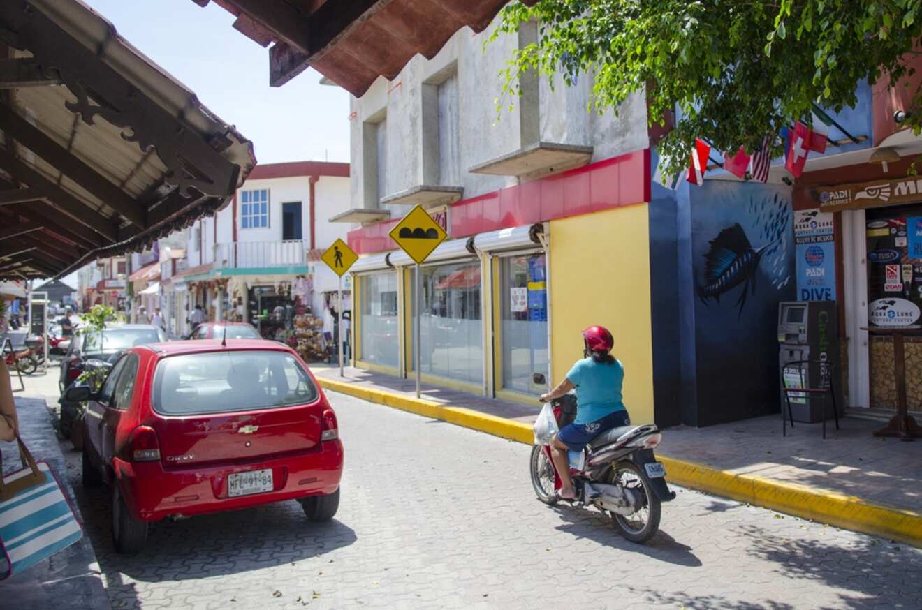 A man riding a motorcycle down a narrow street.