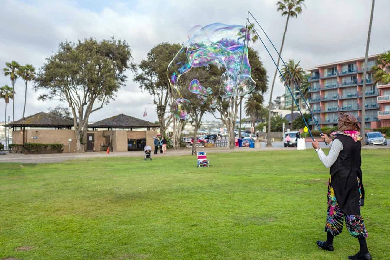 A woman blowing soap bubbles in a park.