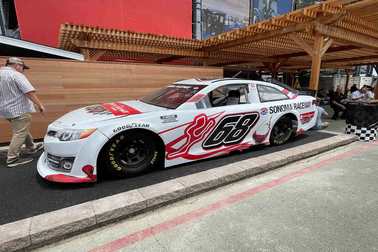 A white nascar car is on display in a parking lot.