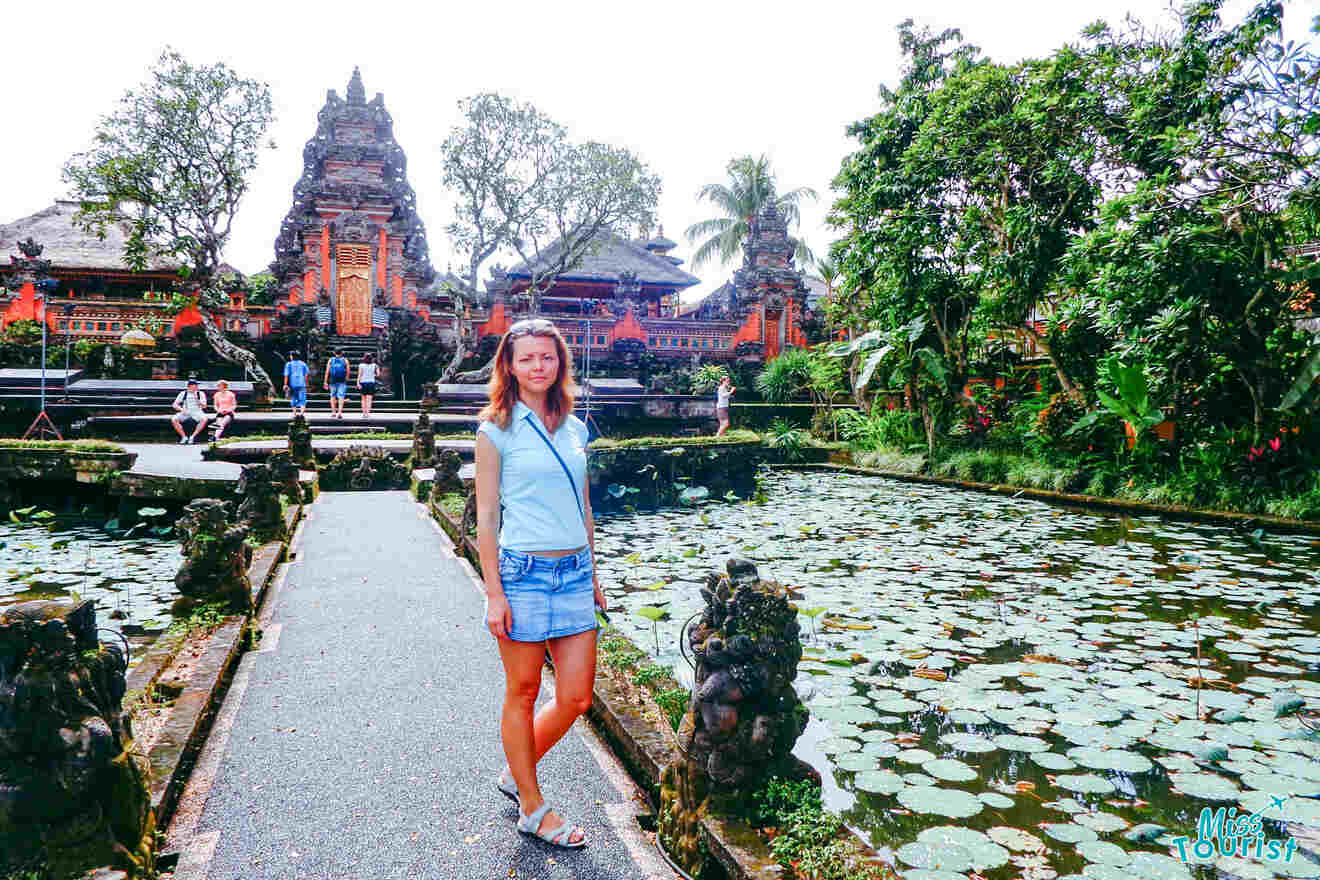 A woman standing in front of a temple with lily ponds.