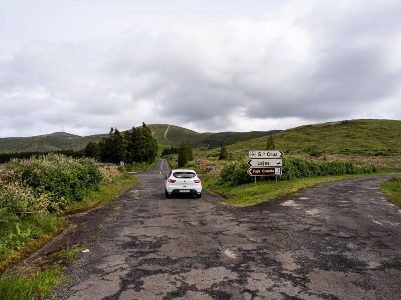 A car is parked on a road in the middle of a grassy field.