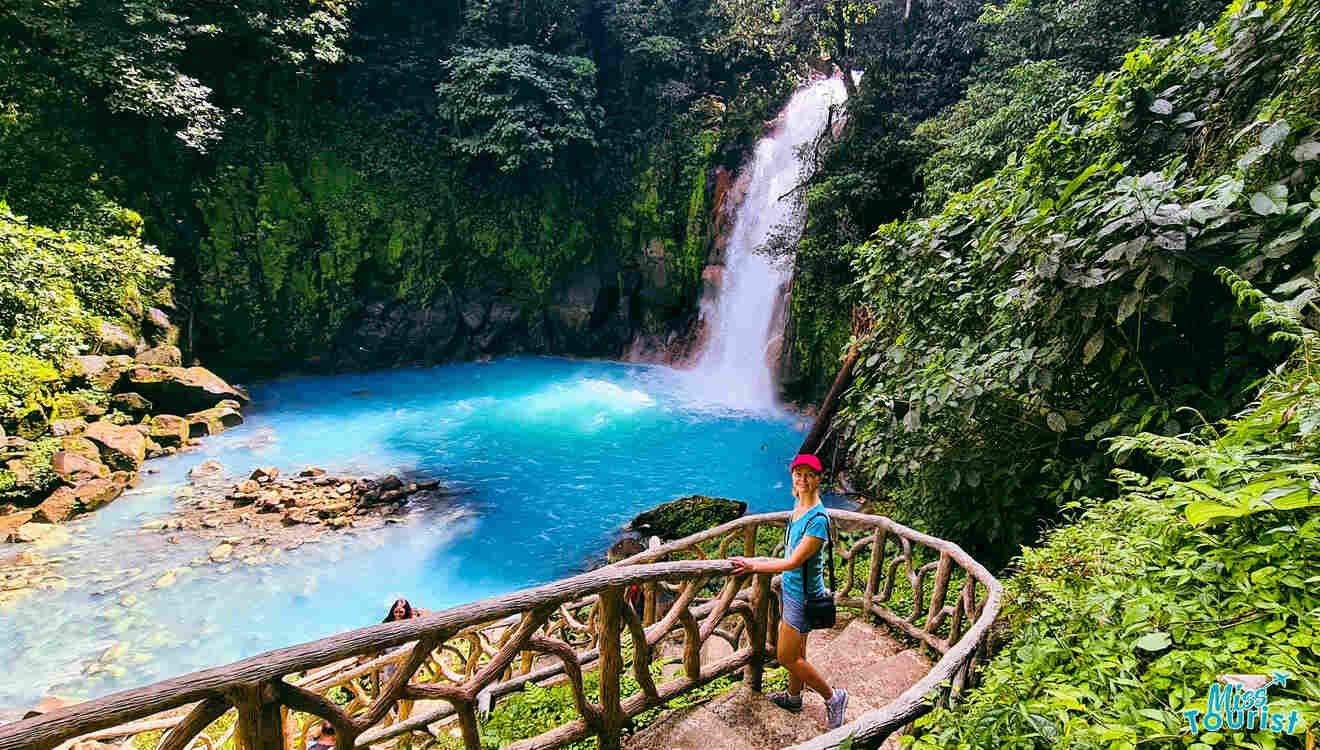 A woman standing next to a waterfall in the jungle.