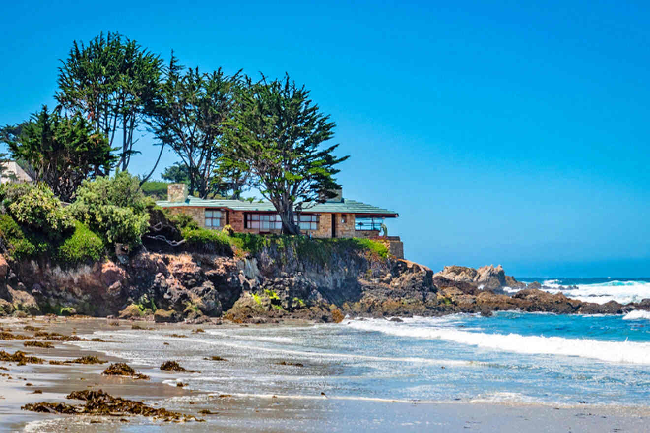 A house sits on a rocky beach next to the ocean.