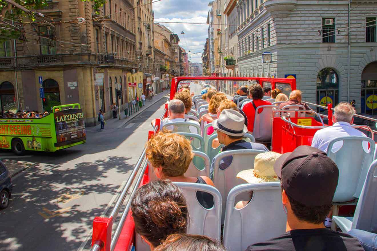 A group of people riding on a red bus in a city.