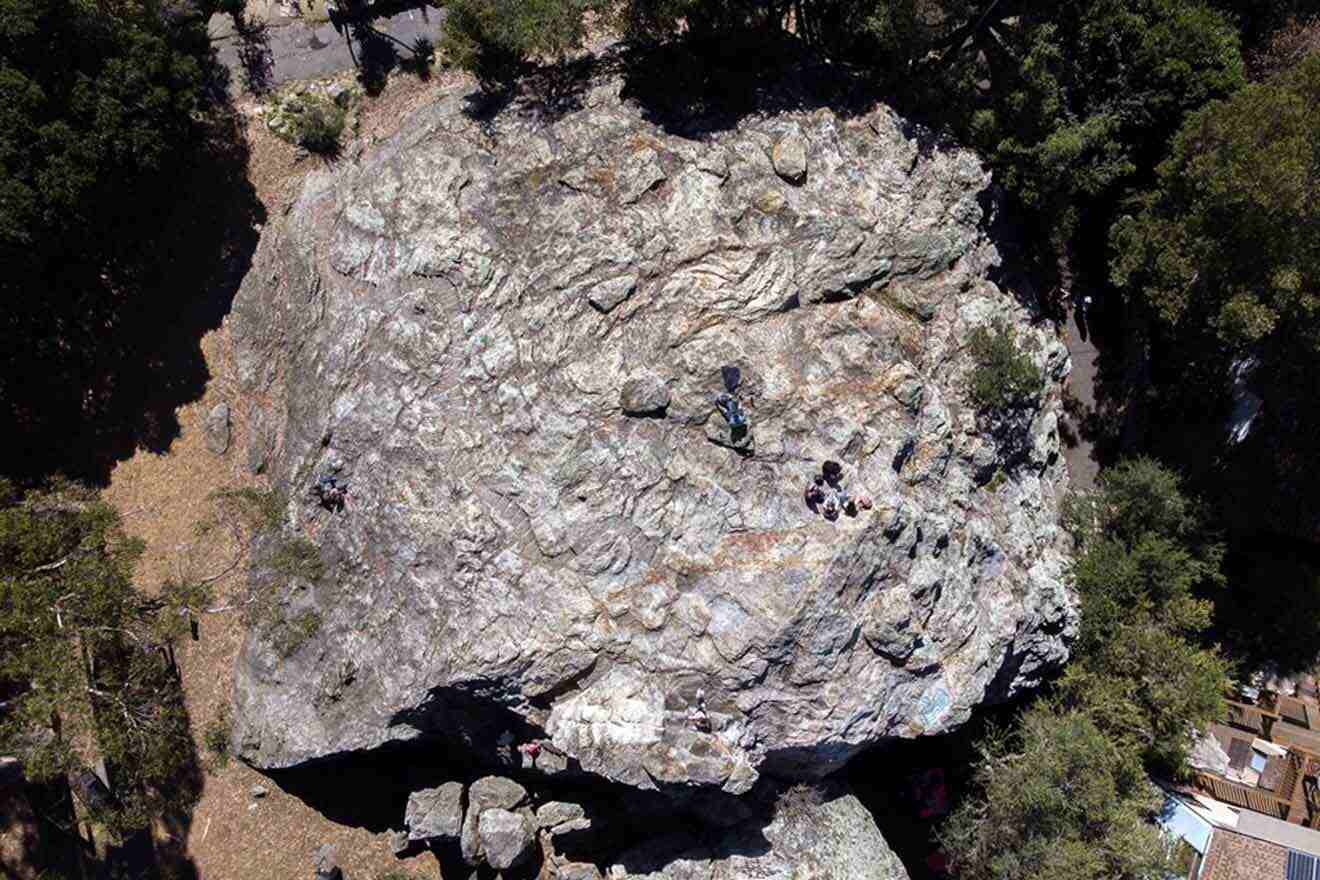 An aerial view of a large rock with people climbing on it.