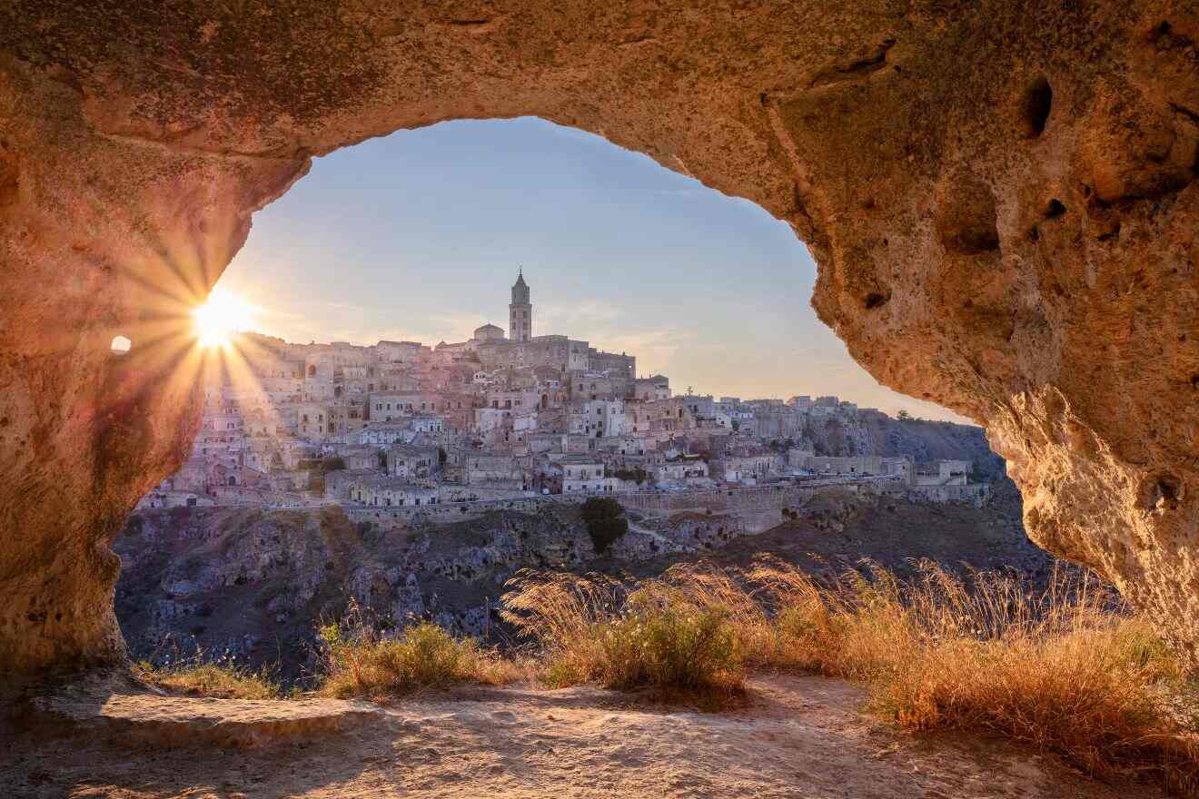 The sun is shining through a cave into a city.