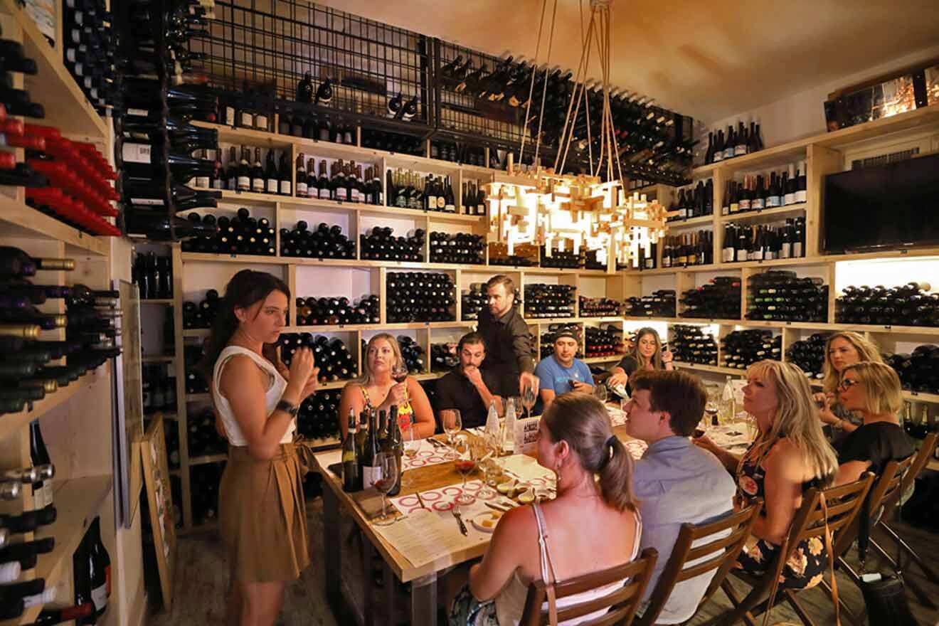 A group of people sitting at a table in a wine cellar.