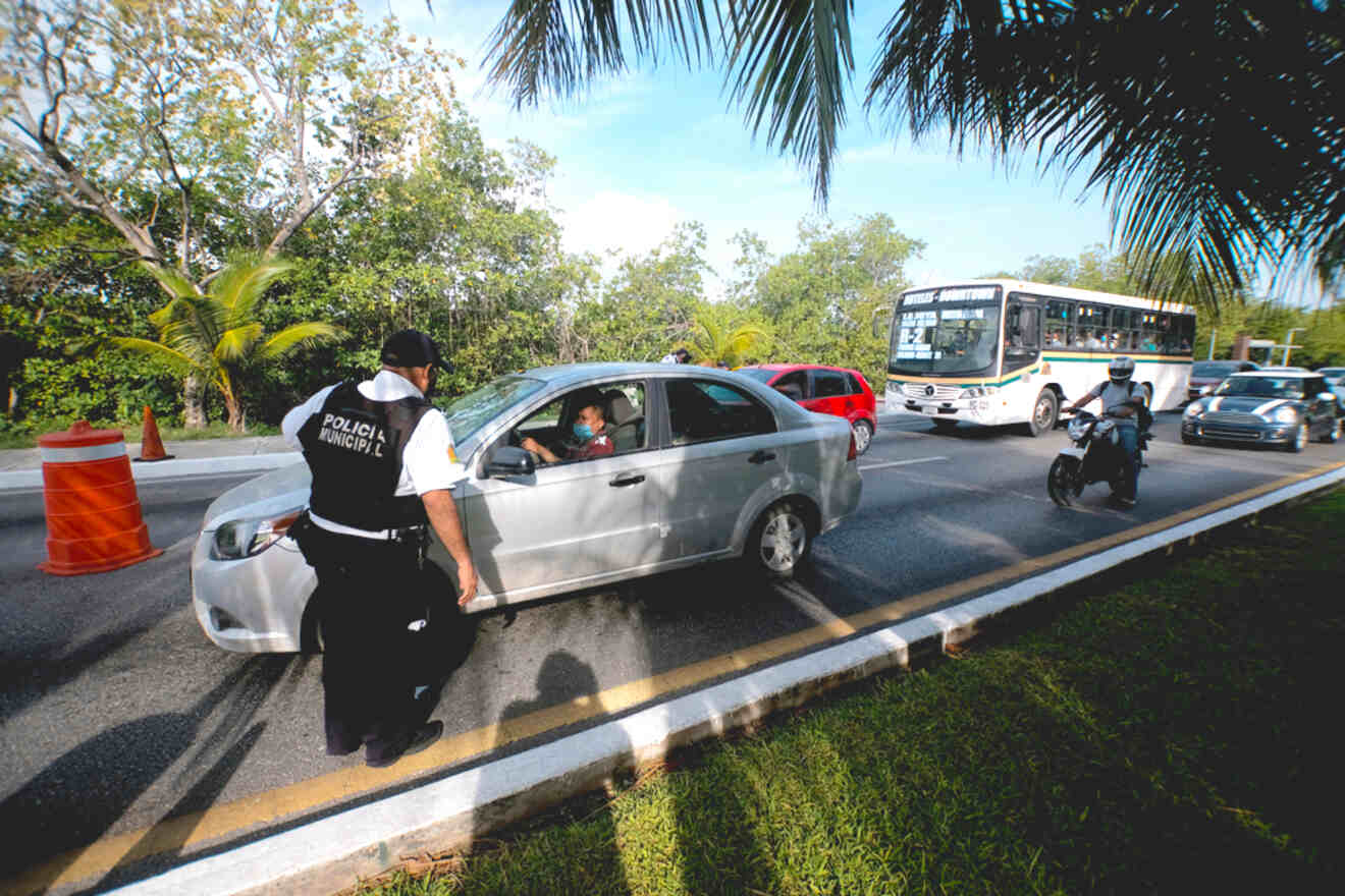 A police officer is standing next to a car on a road.