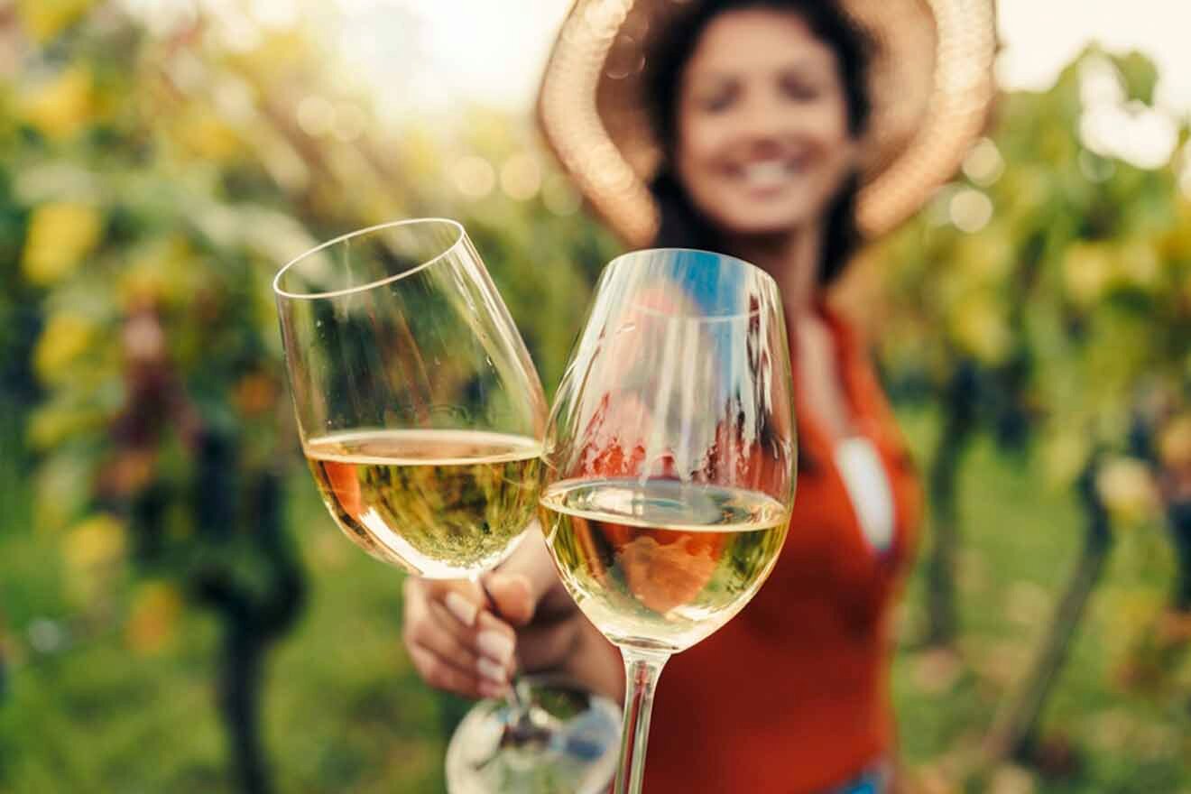 a woman in a straw hat holding a glass of wine