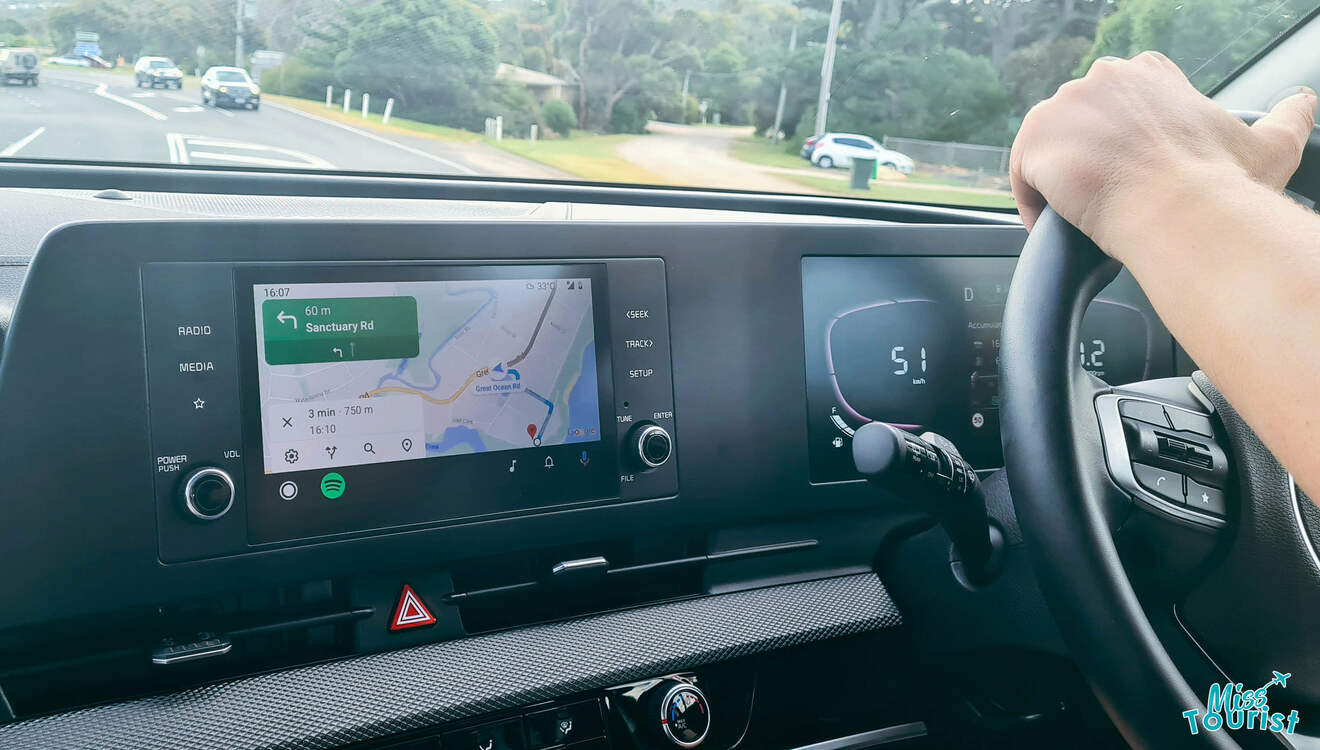 A person is driving a car with a gps on the dashboard.